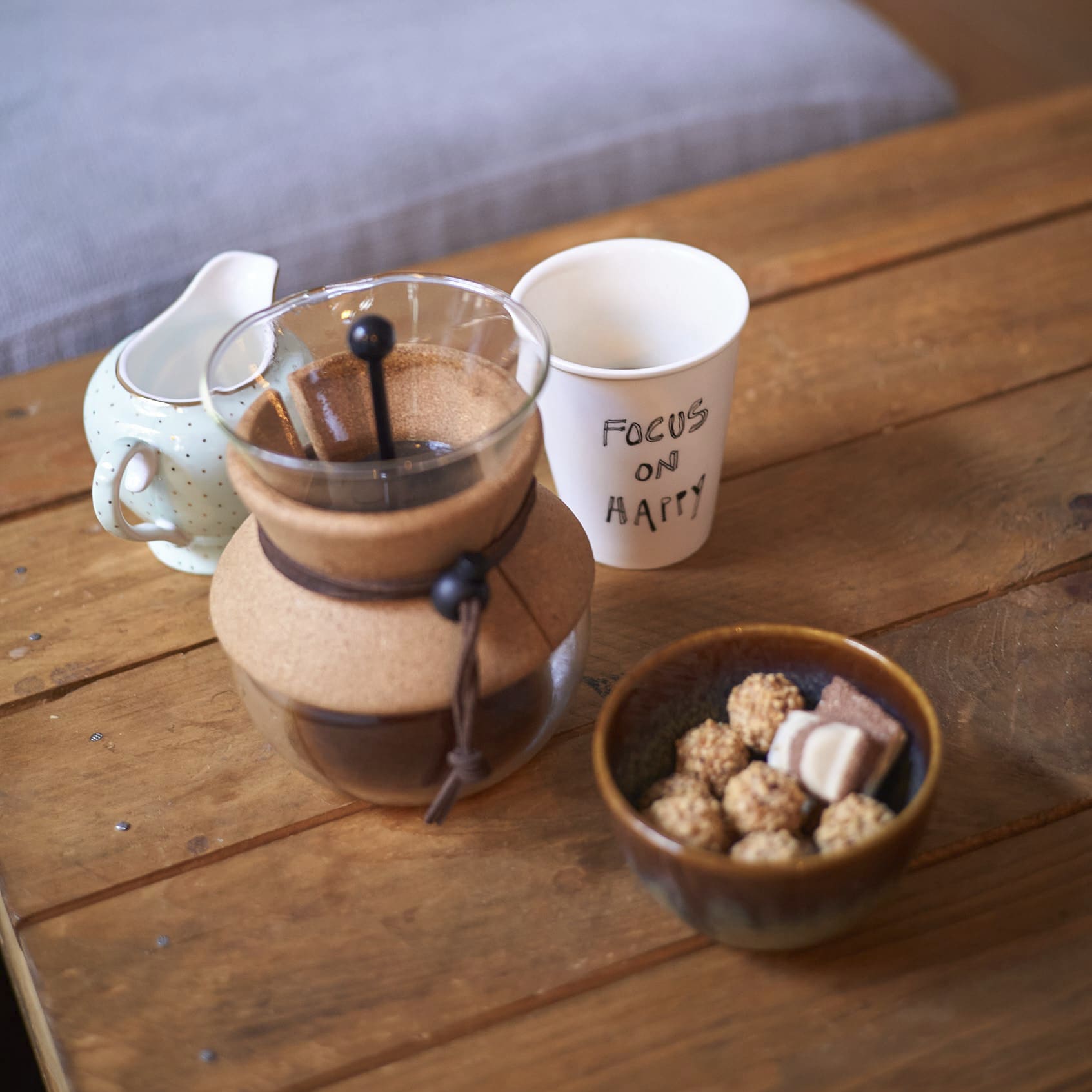 Kaffeekanne mit Becher und kleinem Snack auf Holztisch