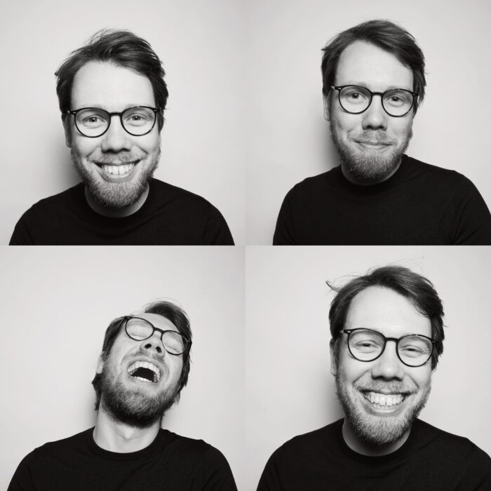 Bastian Schroeder vor weißem Hintergrund lacht in die Kamera